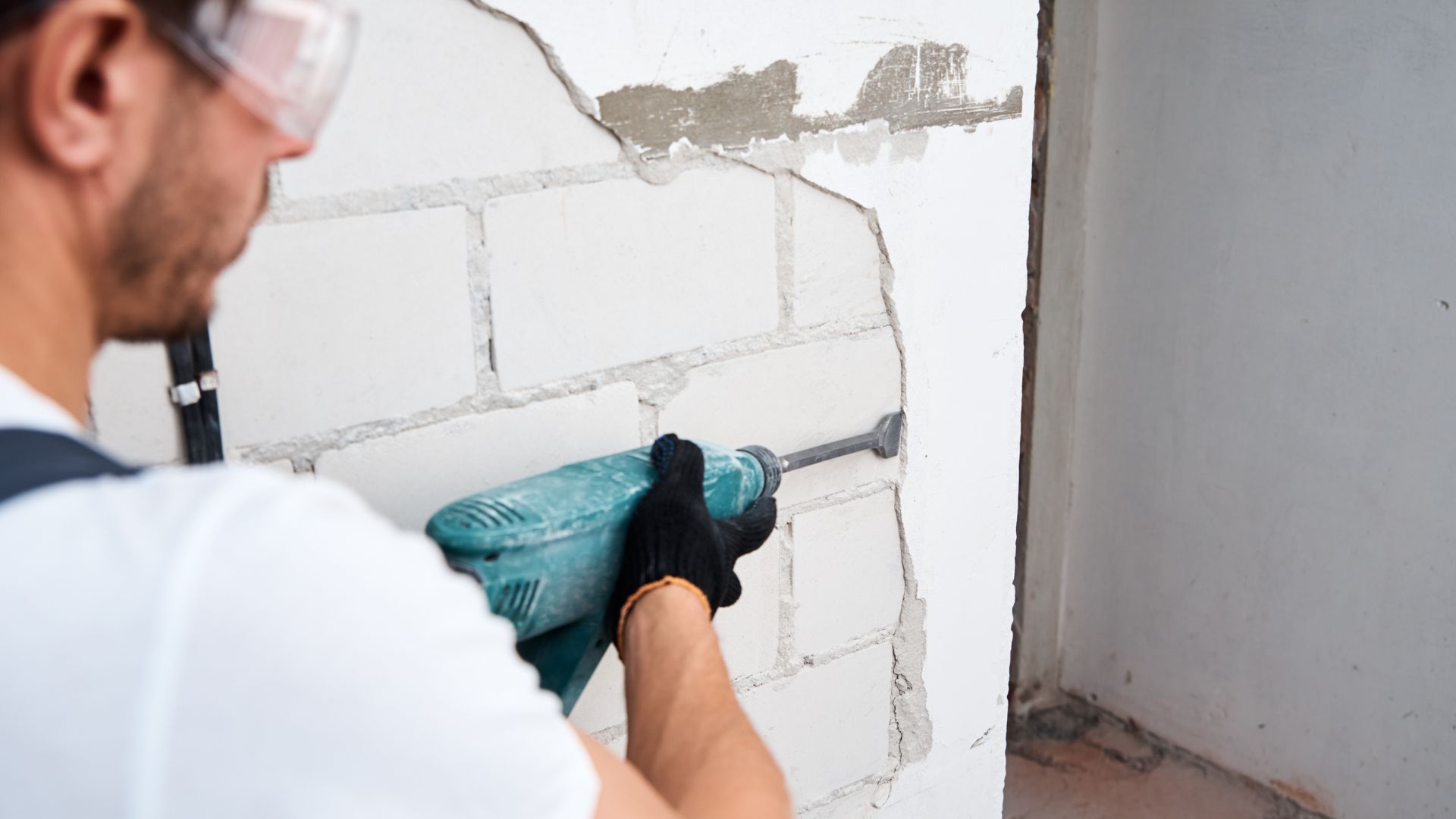 Man with Demolition Hammer Removing Stucco from Wall