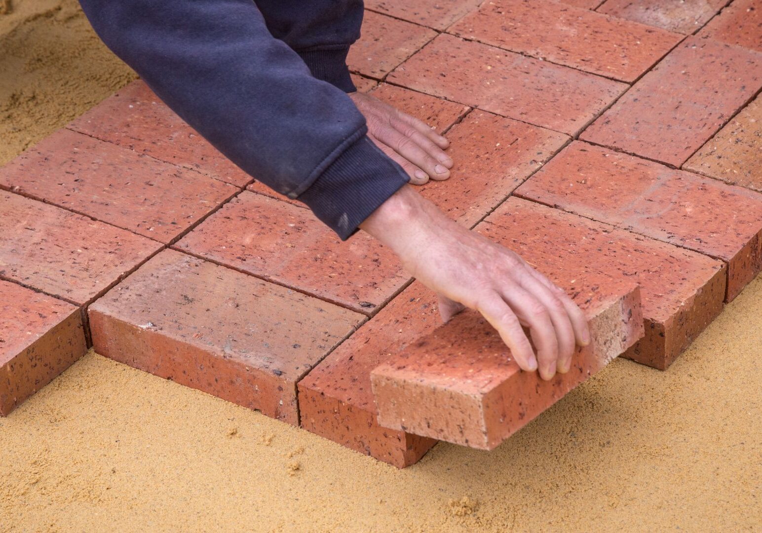 Crop faceless man laying bricks on ground Crop faceless man laying bricks on ground